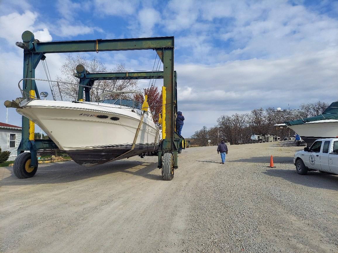 A boat being lifted by crane on the beach.